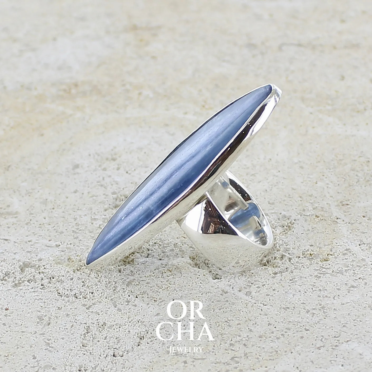 détail du sertissage d'une bague marquise pour femme en argent massif sertie d'un cabochon de cyanite de couleur bleu jean nacré. Pierre translucide à inclusions. Bijou unique réalisée en taille 58 par Orchajewelry