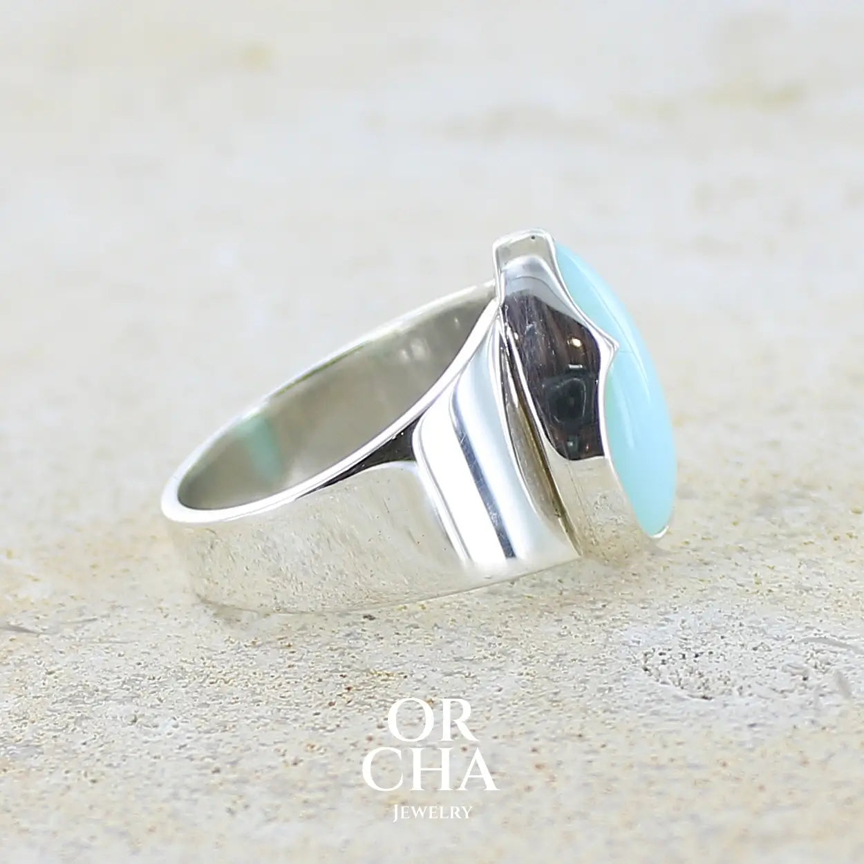 Détail du sertissage d'une bague pour femme en argent massif, sertie d'un cabochon d'opale bleue du Pérou de couleur bleu ciel. Pierre taillée en forme de goutte de qualité opaque. Bijou unique de taille 56