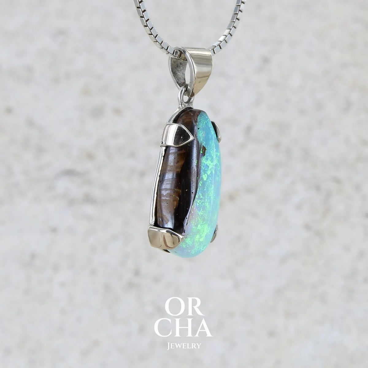 detail du sertissage d'un Pendentif pour femme en or 9k et argent massif serti d'une opale boulder cristal aux feux étoilés multicolores à dominantes bleu turquoise. Cabochon de 7 carat taillé en forme de goutte de qualité translucide. Opale massive australienne. Bijou unique réalisé par Orchajewelry