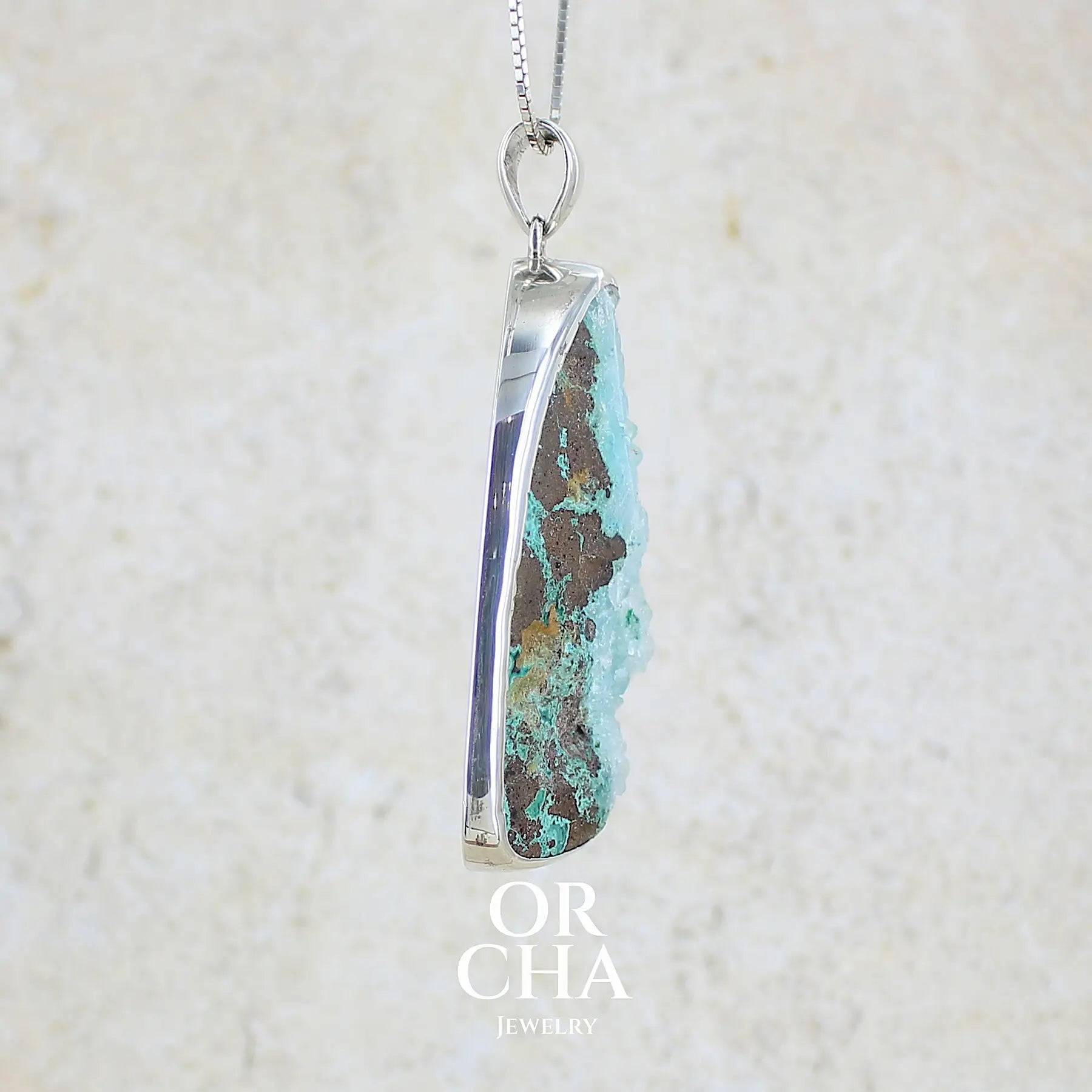 détail texture d'un pendentif en argent massif serti d'un magnifique gemsilica druze: chrysocolle silicifiée recouverte de fins cristaux de quartz scintillant. Pierre de qualité opaque brute en forme de goutte. Pierre naturelle originaire du Mexique de couleur bleue ciel turquoise claire.